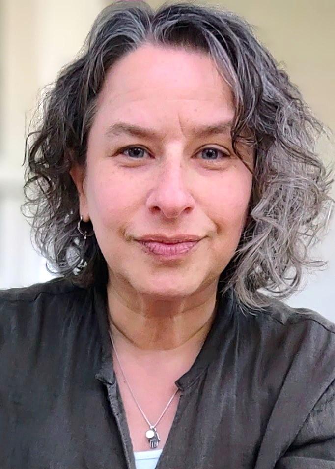 Headshot of smiling, curly-haired woman in olive green shirt