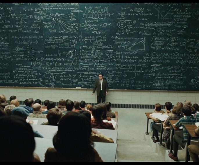 classroom with professor in front of large chalkboard