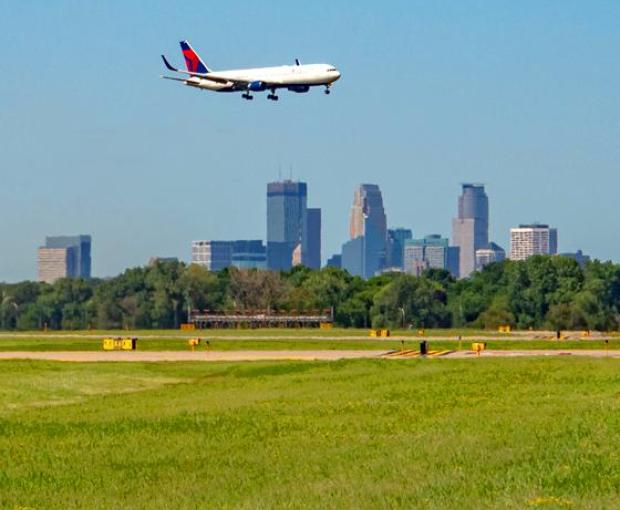 A plane flying over the Minneapolis city skyline on a sunny day