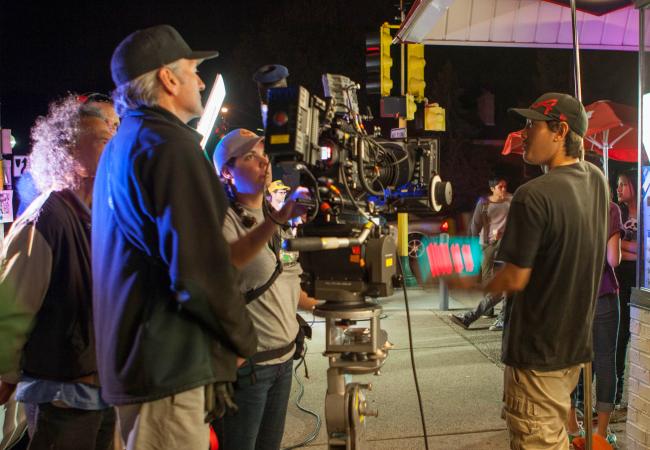 A film crew standing around a camera. 