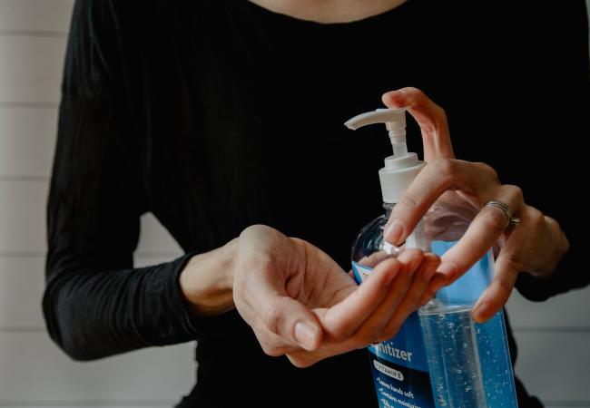 Woman applying hand sanitizer from a pump bottle